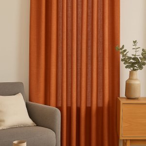 Sfeerimpressie van terrakleurige gordijnen uit de Elegance collectie in een warm en elegant interieur.