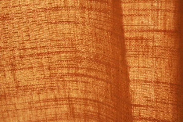 Stofstructuur goed zichtbaar van okergele Elegance gordijnen, lichtdoorlatend effect
