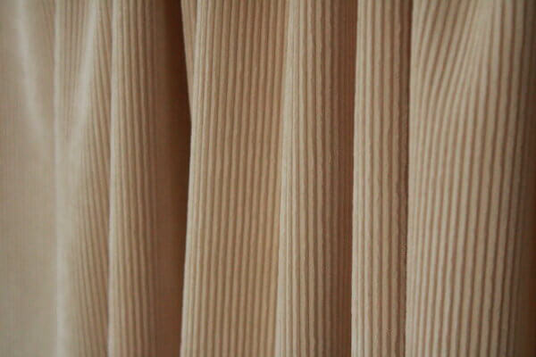 Crèmekleurig Corduroy gordijn, jc2410 van okika. Vloeiend vallend, perfect voor een minimalistisch en licht interieur.