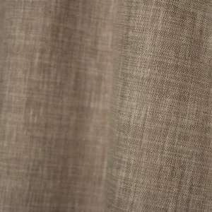 Detailopname van het gemeleerde weefpatroon van de soft taupe inbetween gordijnen met een elegante structuur.