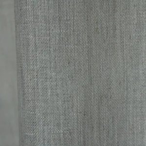 Detailopname van het weefpatroon in zandkleurige inbetween gordijnen met een natuurlijke textuur.