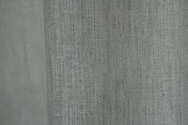 Detailopname van het weefpatroon in zandkleurige inbetween gordijnen met een natuurlijke textuur.
