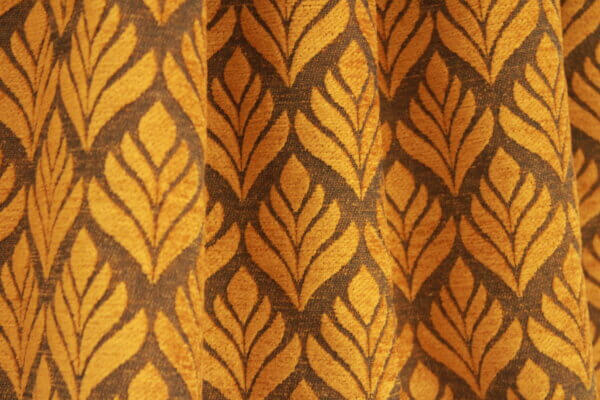 Close-up van gordijnen met retro oker bloemenpatroon, model BB2421 van Okika. Ideaal voor een warme vintage uitstraling in elk interieur.
