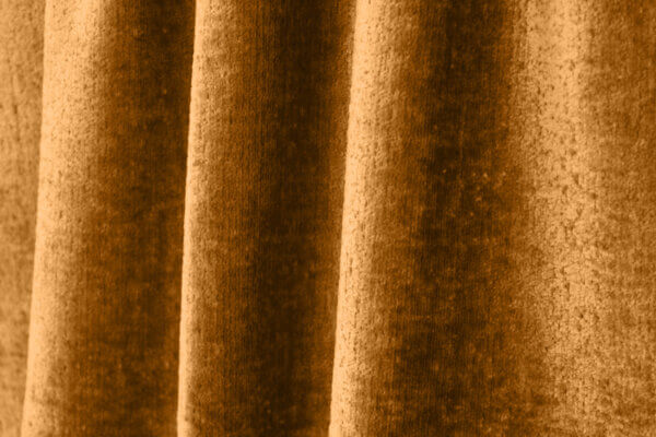 Close-up van een vintage velours gordijn in okerkleur, model BB2412 'Okika'. De luxe velourstructuur en warme, diepe tint zorgen voor een elegante en sfeervolle uitstraling.