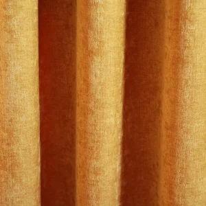 Okergele velours gordijn van Okika, met een zachte chenille-achtige textuur en subtiel krijt-effect, die in deze foto een sfeervolle uitstraling geven aan de ruimte."