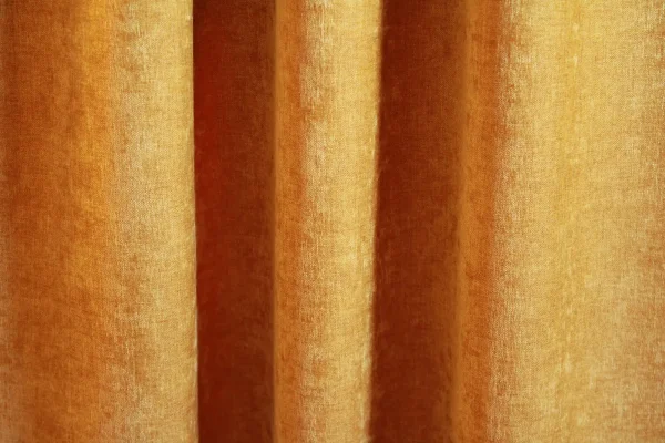 Okergele velours gordijn van Okika, met een zachte chenille-achtige textuur en subtiel krijt-effect, die in deze foto een sfeervolle uitstraling geven aan de ruimte."