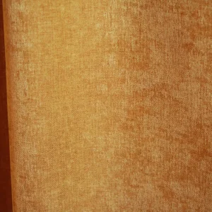 details van okergele velours gordijnstof van Okika, met een luxe, chenille-achtige structuur en een subtiel krijt-effect voor een zachte uitstraling