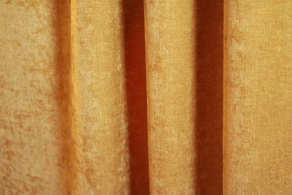 Velours gordijnen van Okika in een warme okergele tint, met een zachte, chenille-achtige textuur en subtiel krijt effect