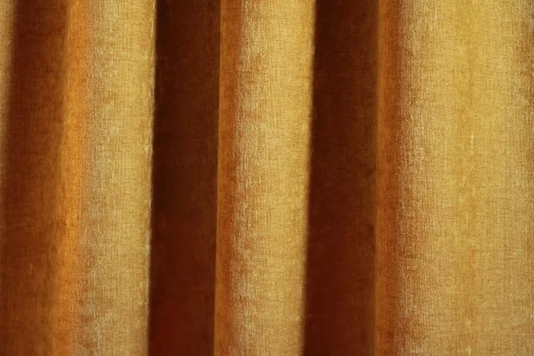 Okergele velours gordijnen van Okika, met een zachte chenille achtige textuur en subtiel krijt-effect, zoals te zien in deze sfeervolle impressie van de gordijnen in een warme ruimte.