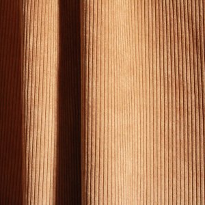 Ribstof gordijnen in cognac kleur van Okika in een sfeervol interieur.