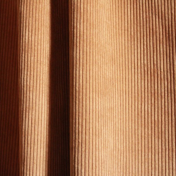 Ribstof gordijnen in cognac kleur van Okika in een sfeervol interieur.