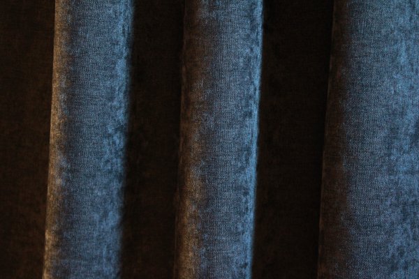 Donkerblauwe velours gordijnen van Okika, met een chenille-achtige structuur en subtiele krijt-effecten verwerkt in de stof, voor een uniek en opvallend effect.