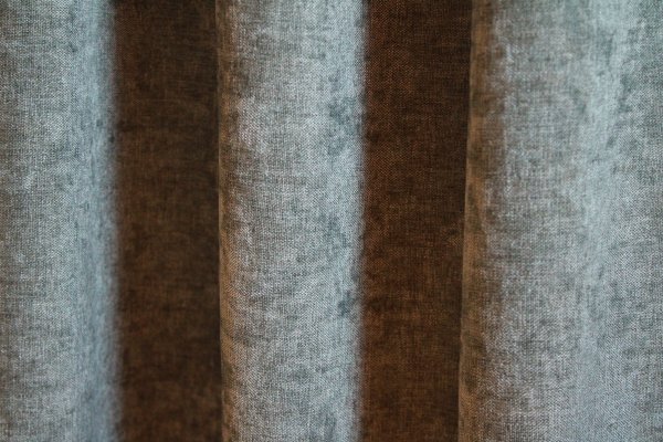 Groengrijze velours gordijnen van Okika met een subtiel krijt-effect, die een luxe en rustgevende sfeer creëren in elke kamer.