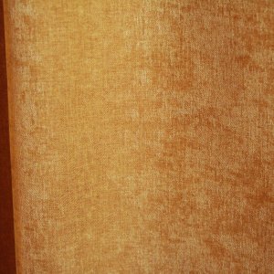details van okergele velours gordijnstof van Okika, met een luxe, chenille-achtige structuur en een subtiel krijt-effect voor een zachte, diepe uitstraling."