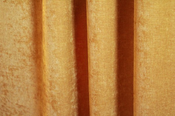 Velours gordijnen van Okika in een warme okergele tint, met een zachte, chenille-achtige textuur en subtiel krijt effect