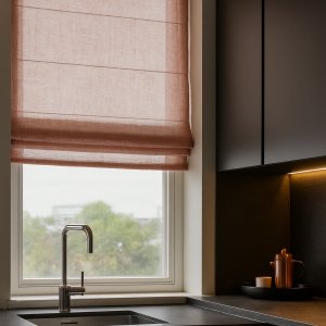 Sfeerimpressie van vouwgordijn in Zen Weave terra stof in een warm interieur met natuurlijke lichtinval en zachte uitstraling