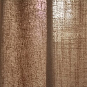 Detail van de stofstructuur van het beige gordijn uit de Elegance collectie, model JC2548 Okika. De fijn geweven stof is semi lichtdoorlatend: laat natuurlijk daglicht binnen terwijl het zicht naar buiten beperkt blijft.