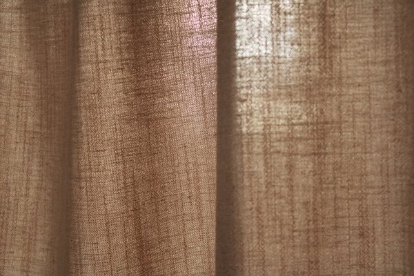 Detail van de stofstructuur van het beige gordijn uit de Elegance collectie, model JC2548 Okika. De fijn geweven stof is semi lichtdoorlatend: laat natuurlijk daglicht binnen terwijl het zicht naar buiten beperkt blijft.