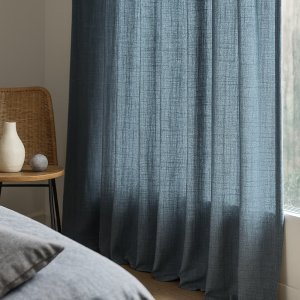 Sfeerimpressie van grijsblauwe gordijnen uit de Florain collectie in een rustige slaapkamer.