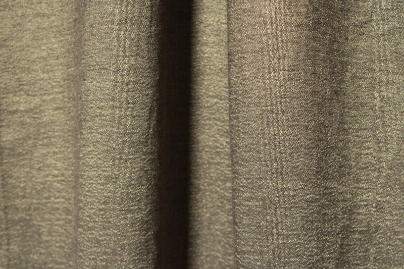 Sfeerfoto van de bronzen linnen gordijnen met lurex uit de Okika collectie, elegant hangend met warme kleurtonen en een subtiele glinstering in het licht