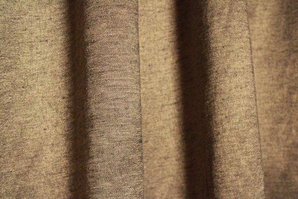 Stofdetails van de bronzen linnen gordijnen met lurex uit de Okika collectie, met zicht op de warme kleurtint, linnenstructuur en subtiele metallic glans
