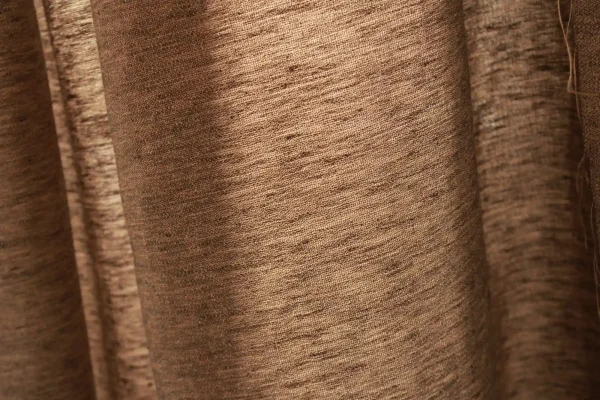 Stofstructuur van de bronzen linnen gordijnen met lurex uit de Okika collectie, met zicht op de natuurlijke vezels en glinsterende metallic draad.