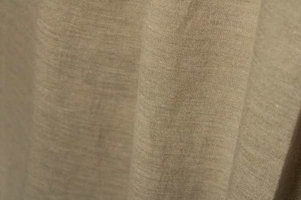 Stofpatroon van de champagne kleurige linnen gordijnen met lurex uit de Okika collectie, recht geplooid met zicht op de natuurlijke structuur en verfijnde metallic glans.