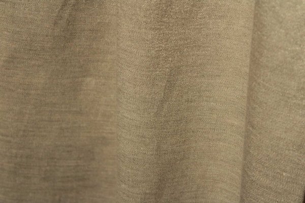 Stofpatroon van de champagne kleurige linnen gordijnen met lurex uit de Okika collectie, recht geplooid met zicht op de natuurlijke structuur en verfijnde metallic glans.