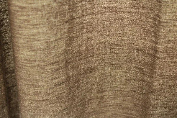 tofstructuur van de taupe kleurige linnen gordijnen met lurex uit de Okika collectie, met zicht op de natuurlijke linnenvezels en subtiele metallic glans.