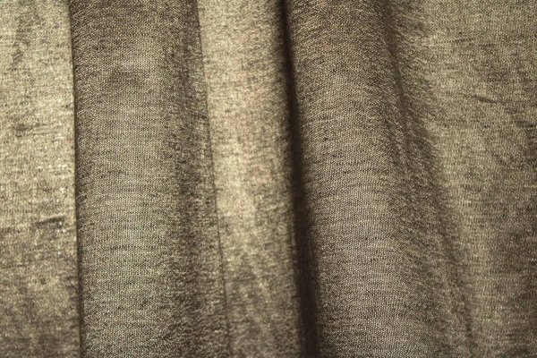 Stofdetails van de taupe kleurige linnen gordijnen met lurex uit de Okika collectie, recht geplooid met zicht op de linnenstructuur en fijne glinstering van het lurexdraad.