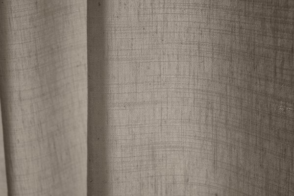 Detailfoto van offwhite gordijnen uit de Elegance collectie, model JC2545 Okika. De stofstructuur toont een fijn geweven patroon met een semi lichtdoorlatende eigenschap. De stof is kleurvast en slijtvast, ideaal voor langdurig gebruik.