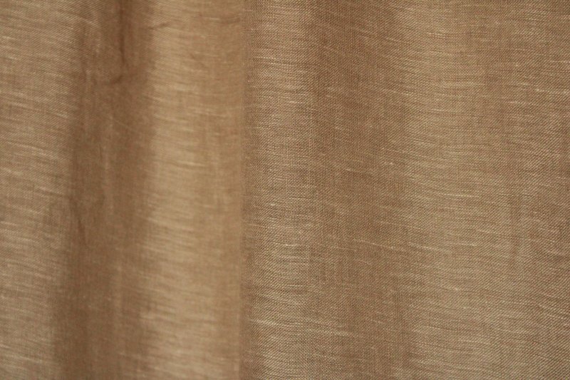 Sfeerfoto van beige linnen inbetween gordijnen uit de Maison collectie van Okika, natuurlijk hangend en zacht licht doorlatend door de transparante eigenschap