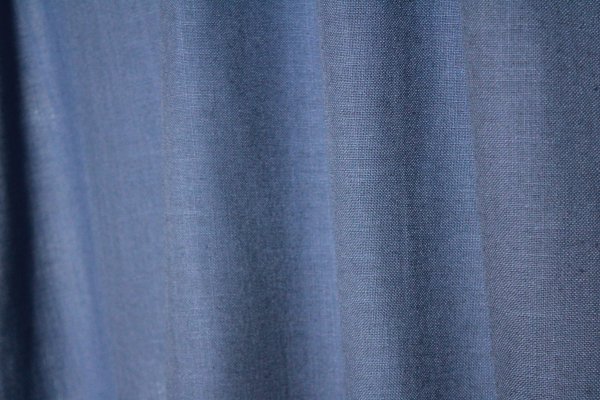 Sfeerfoto van denimblauwe gordijnen uit de Elegance collectie, model JC2557 Okika. De gordijnen hebben een semi lichtdoorlatende, fijn geweven stof die zacht licht doorlaat. Kleurvast en slijtvast.