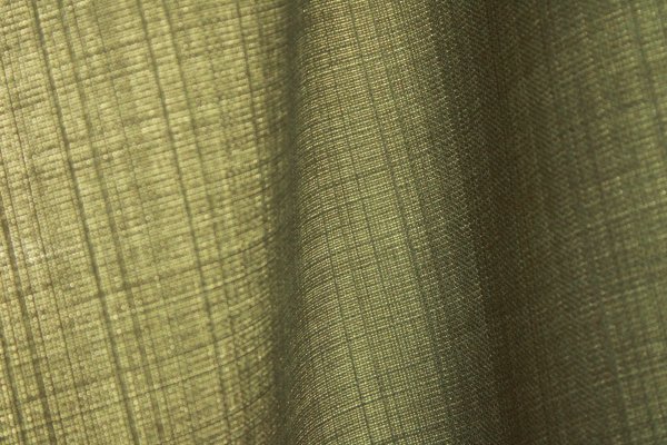 Detailfoto van de stofstructuur van groene gordijnen uit de Florain collectie (JC2534) van Okika, die het licht zachtjes binnen laten voor een levendig effect
