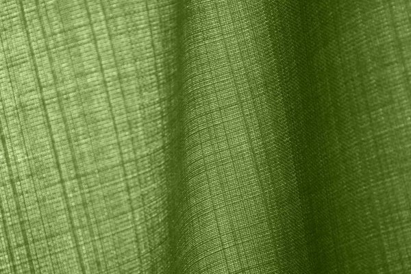 Detailfoto van de stofstructuur van groene gordijnen uit de Florain collectie (JC2534) van Okika, die het licht zachtjes binnen laten voor een levendig effect