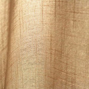 Stofstructuur van ivoorkleurige inbetween gordijnen met linnen look uit de Saphira Light collectie van Okika, lichtdoorlatend en natuurlijk geweven.