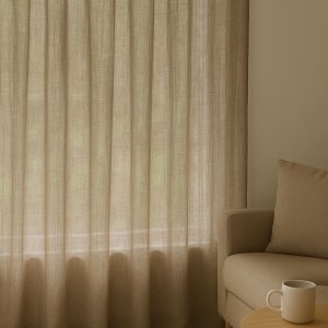 Inbetween gordijnen van 100% linnen in taupe, lichtdoorlatend opgehangen in een sfeervolle interieursetting met natuurlijke materialen.