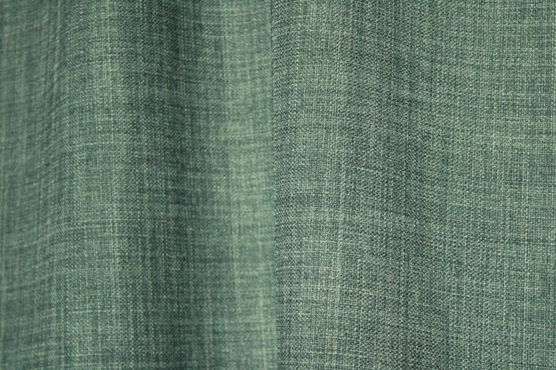 Detailfoto van de stof van petrolkleurige gordijnen uit de Florain collectie (JC2525) van Okika, met een rijke textuur en een elegante, diepe kleurtint. petrol gordijnen op maat