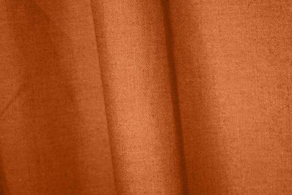 : Sfeerfoto van gordijnen in diepe oranje roestkleur met linnen look uit de Saphira collectie van Okika,
