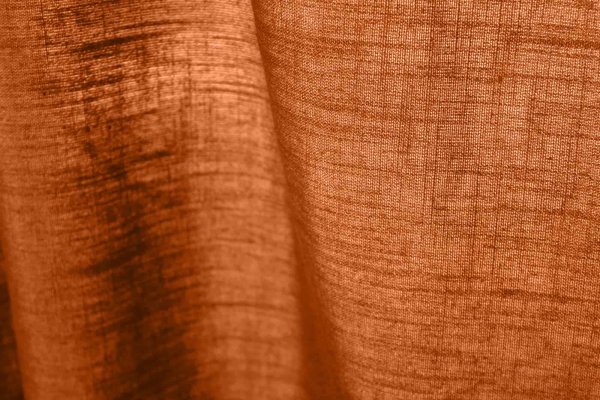 stofstructuur van gordijnen in diepe oranje roestkleur met linnen look uit de Saphira collectie van Okika, semi lichtdoorlatend met zichtbare weving.