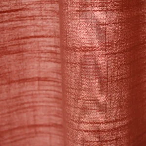 Close-up van de stofstructuur van roze gordijnen uit de Saphira-collectie van Okika filterd het daglicht zacht en goed zichtbaar