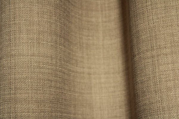 Close-up van het stofpatroon van soft taupe gordijnen uit de Florain collectie (JC2516) van Okika, met een subtiele weving die veel sfeer geeft door gemeleerd effect