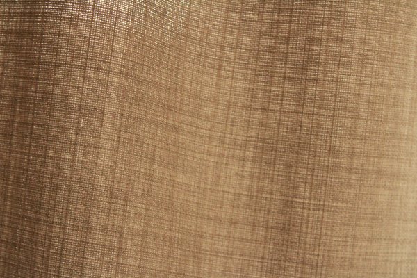 Detailfoto van de stofstructuur van soft taupe gordijnen uit de Florain collectie (JC2516) van Okika, met een fijne weefstructuur die zorgt voor een levendig effect met het daglicht