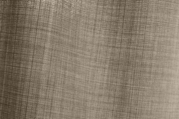 Detailfoto van de stofstructuur van soft taupe gordijnen uit de Florain collectie (JC2516) van Okika, met een fijne weefstructuur die zorgt voor een levendig effect met het daglicht