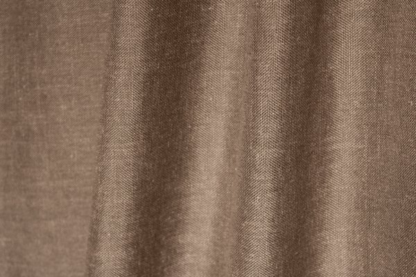 Sfeerfoto van de taupekleurige inbetween gordijnen met linnen look uit de Saphira Light collectie van Okika, soepel hangend en zacht licht doorlatend voor een warme sfeer.
