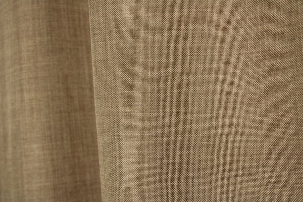 Stofdetails van taupekleurig inbetween gordijn uit de Norena collectie van Okika, met zicht op de gemêleerde en wollige stofstructuur