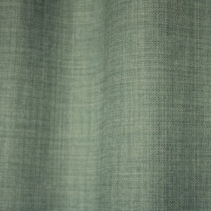 Detailfoto van van turquoise gordijnen uit de Florain collectie (JC2526) van Okika, met een levendige kleur die de ruimte op vrolijkt.