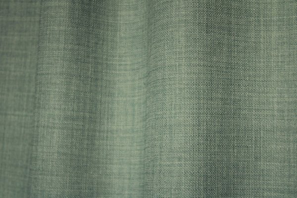 Detailfoto van van turquoise gordijnen uit de Florain collectie (JC2526) van Okika, met een levendige kleur die de ruimte op vrolijkt.