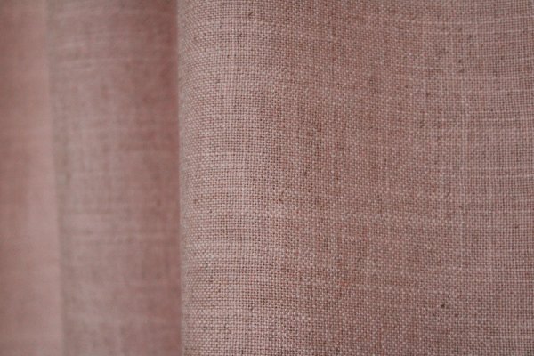 Detailfoto van de stofstructuur van zacht roze Elegance gordijnen uit de JC2561 collectie. Effen gordijnstof met een volle weving en een verfijnde, zachte uitstraling.