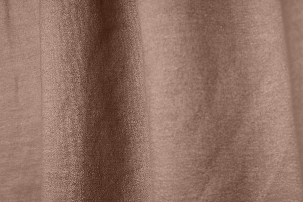 Close-up van roze gordijnstof met linnen en lurex, uit de collectie van Okika, met verfijnde weving en glinsterend effect.